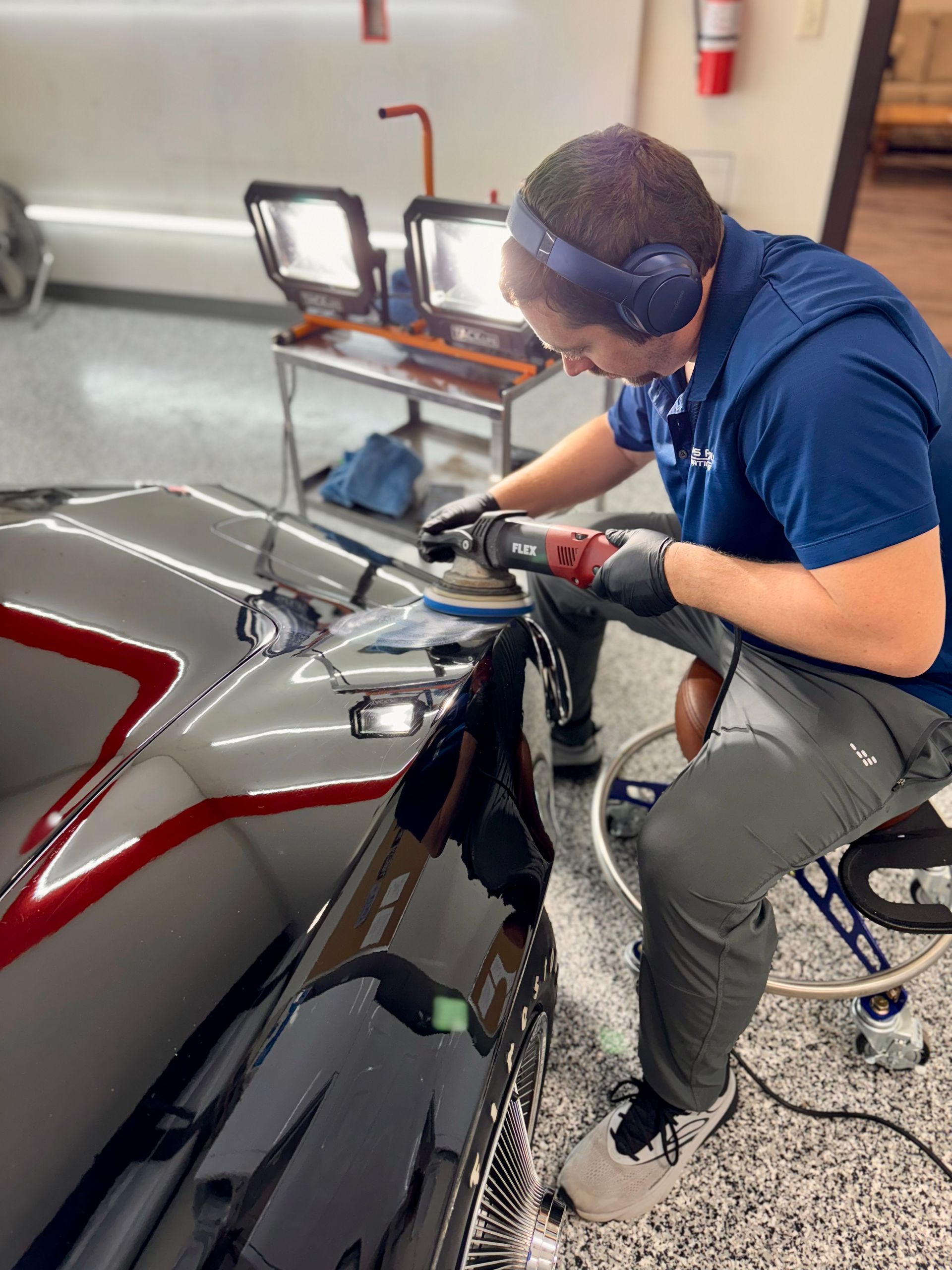 A man is paint correcting a car with a machine polisher.