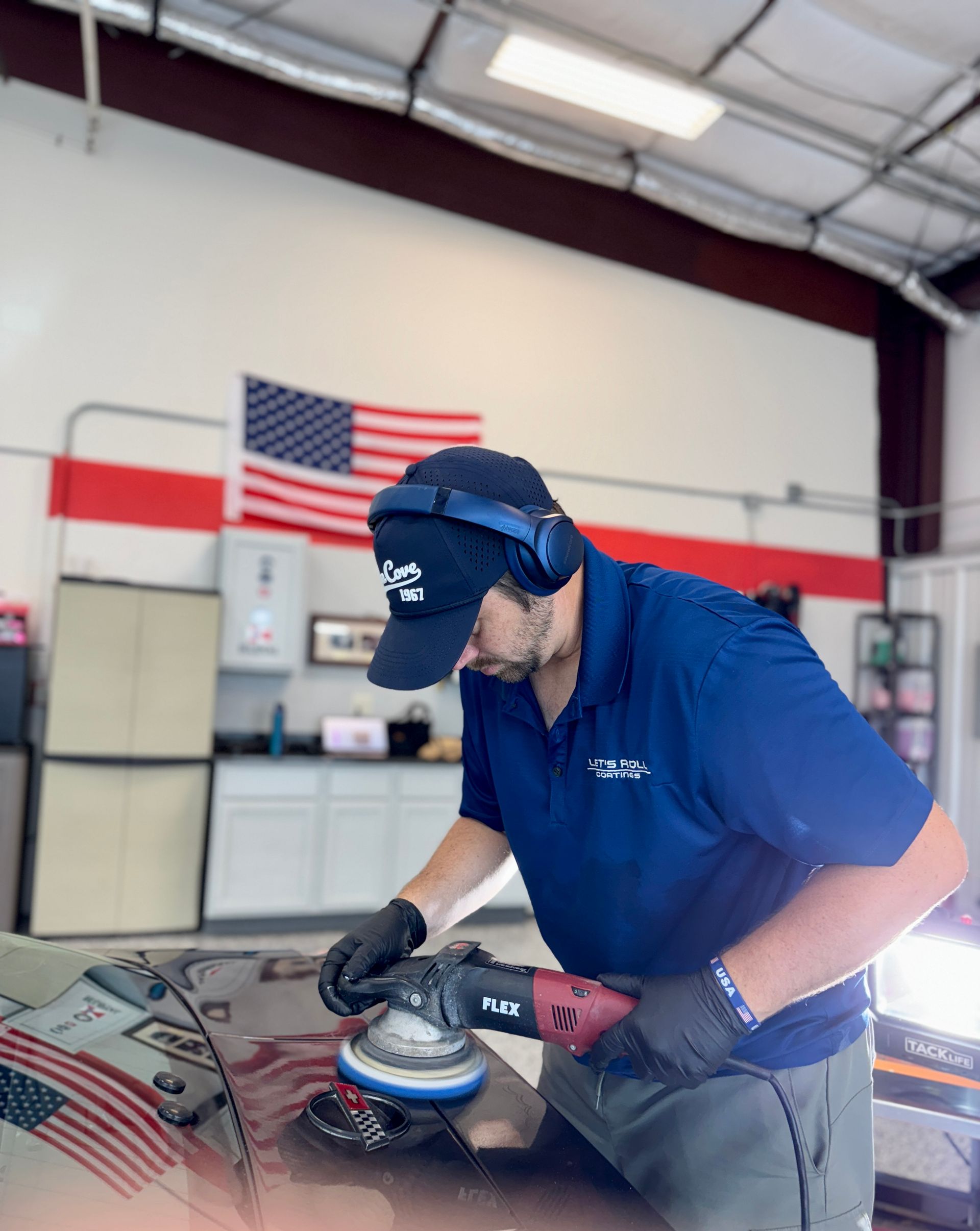 A man is polishing a car door with a machine.