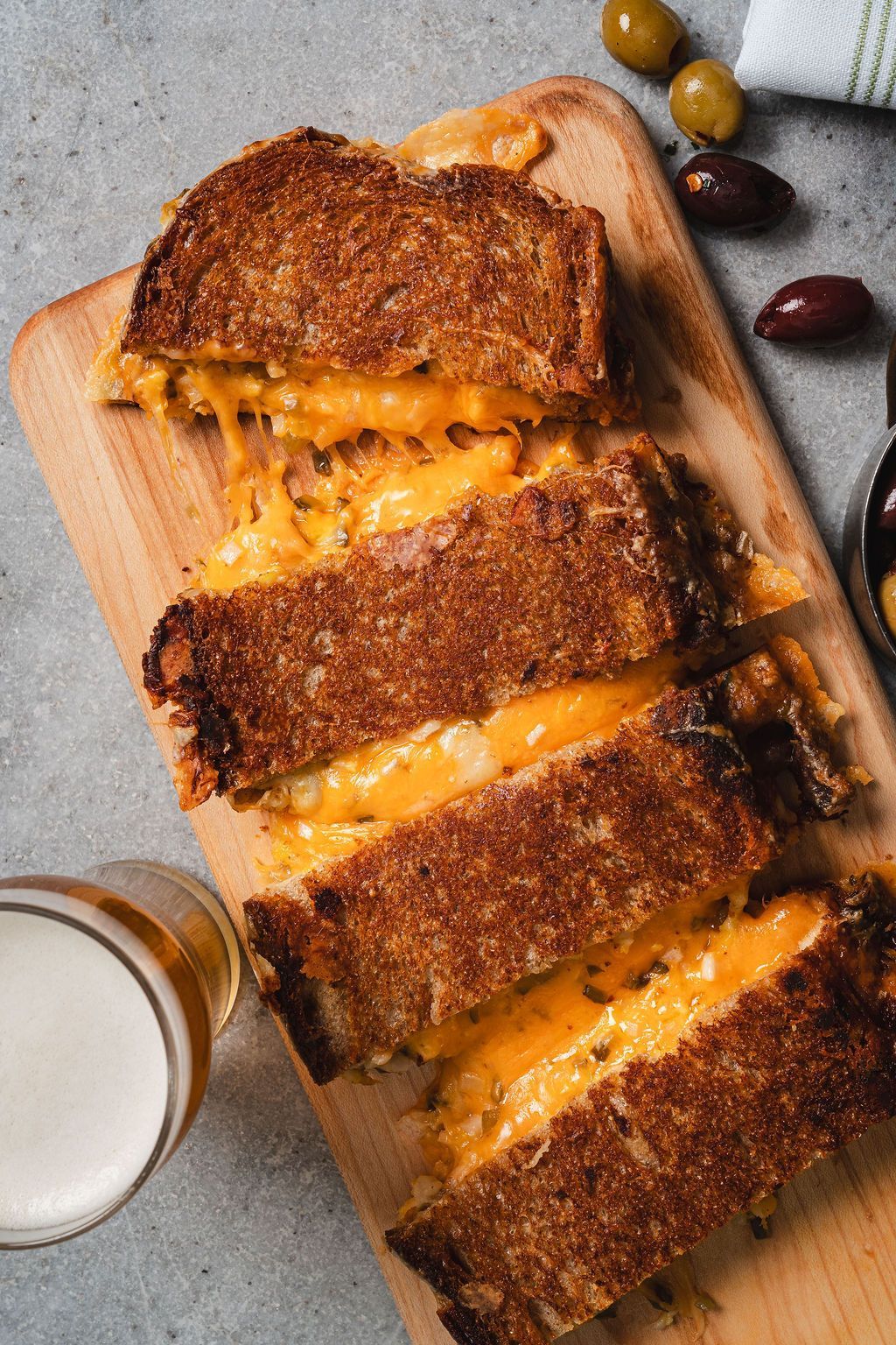 Grilled cheese sandwich sliced on a wooden board.