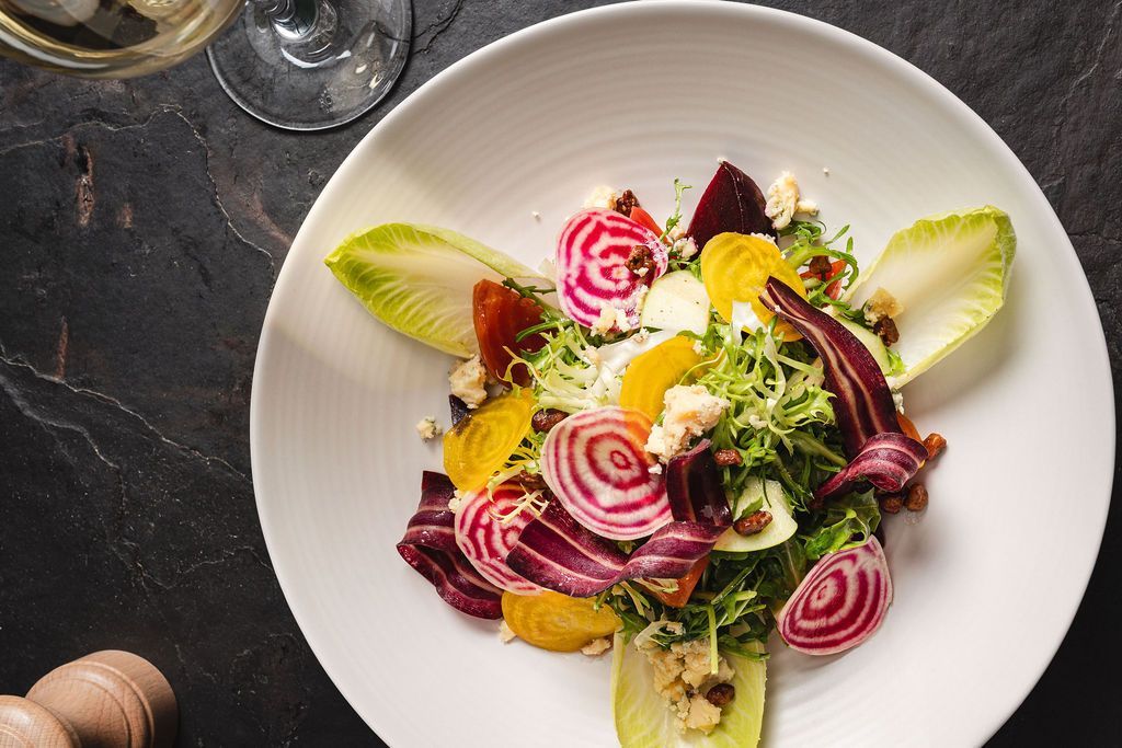 Colorful salad with beet slices, citrus, and greens on a white plate