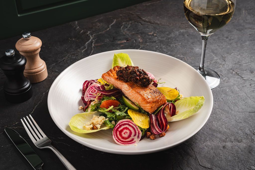 A salad with endive, candy cane radishes, fish,