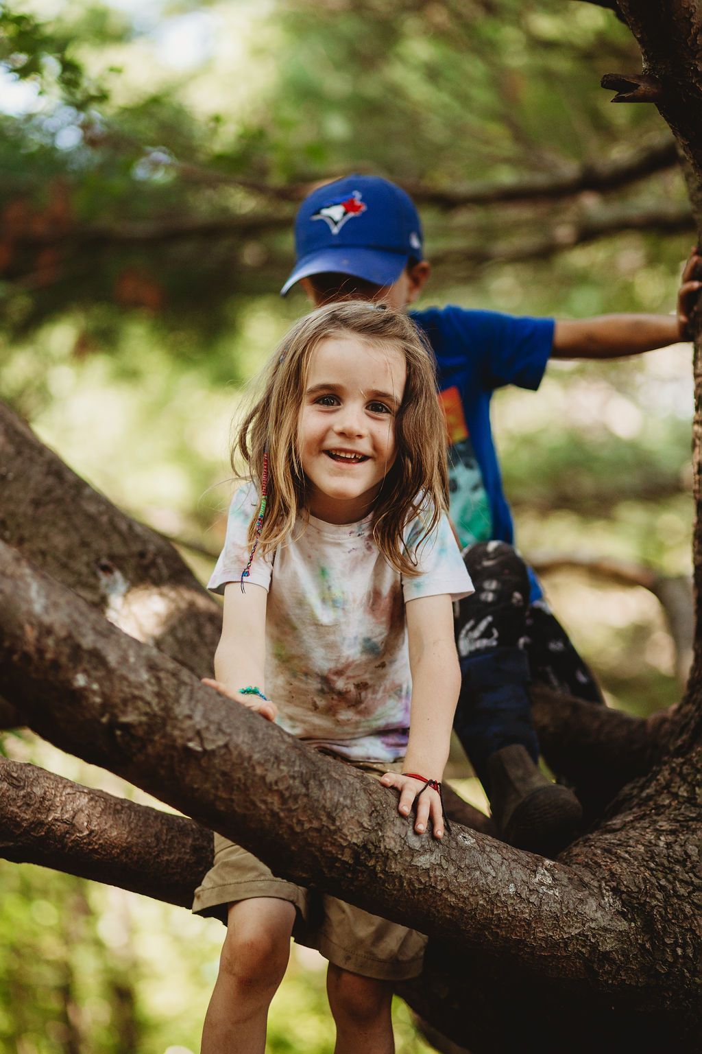 A boy and a girl are climbing a tree branch.