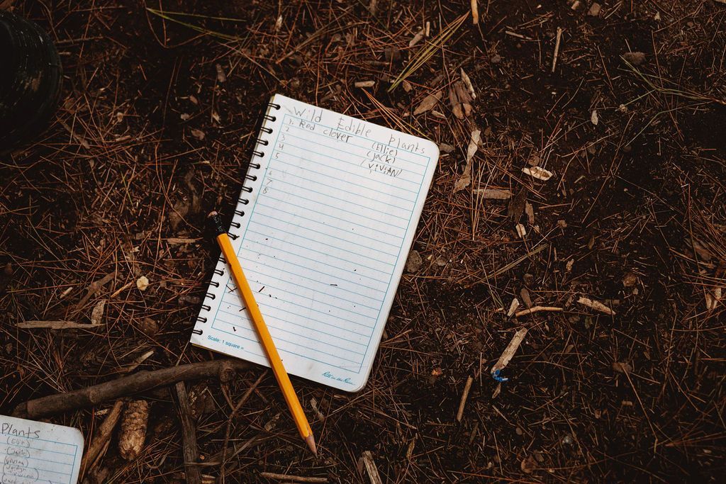 A notebook and a pencil are laying on the ground.