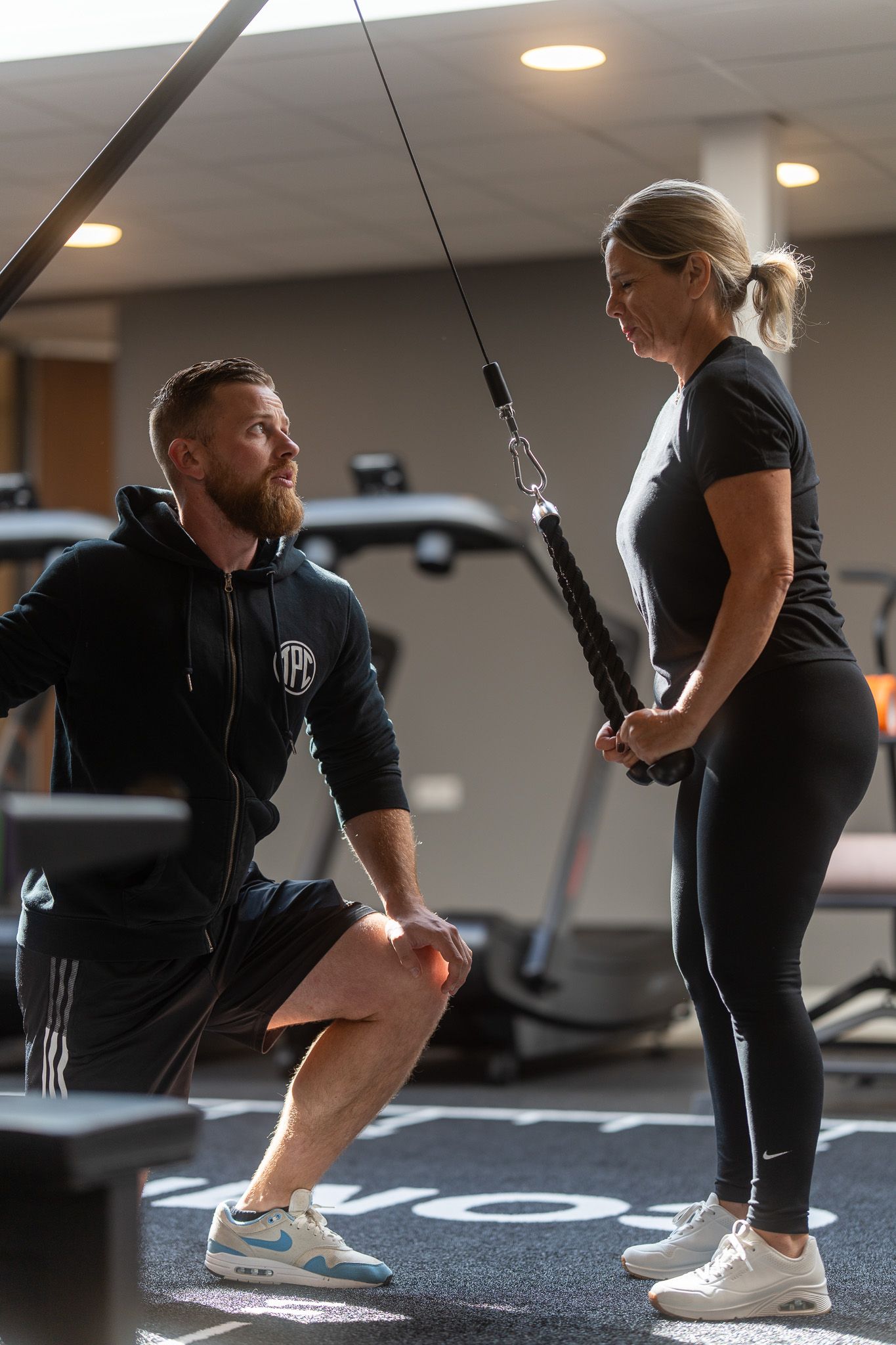 Een man en een vrouw doen oefeningen in een sportschool.