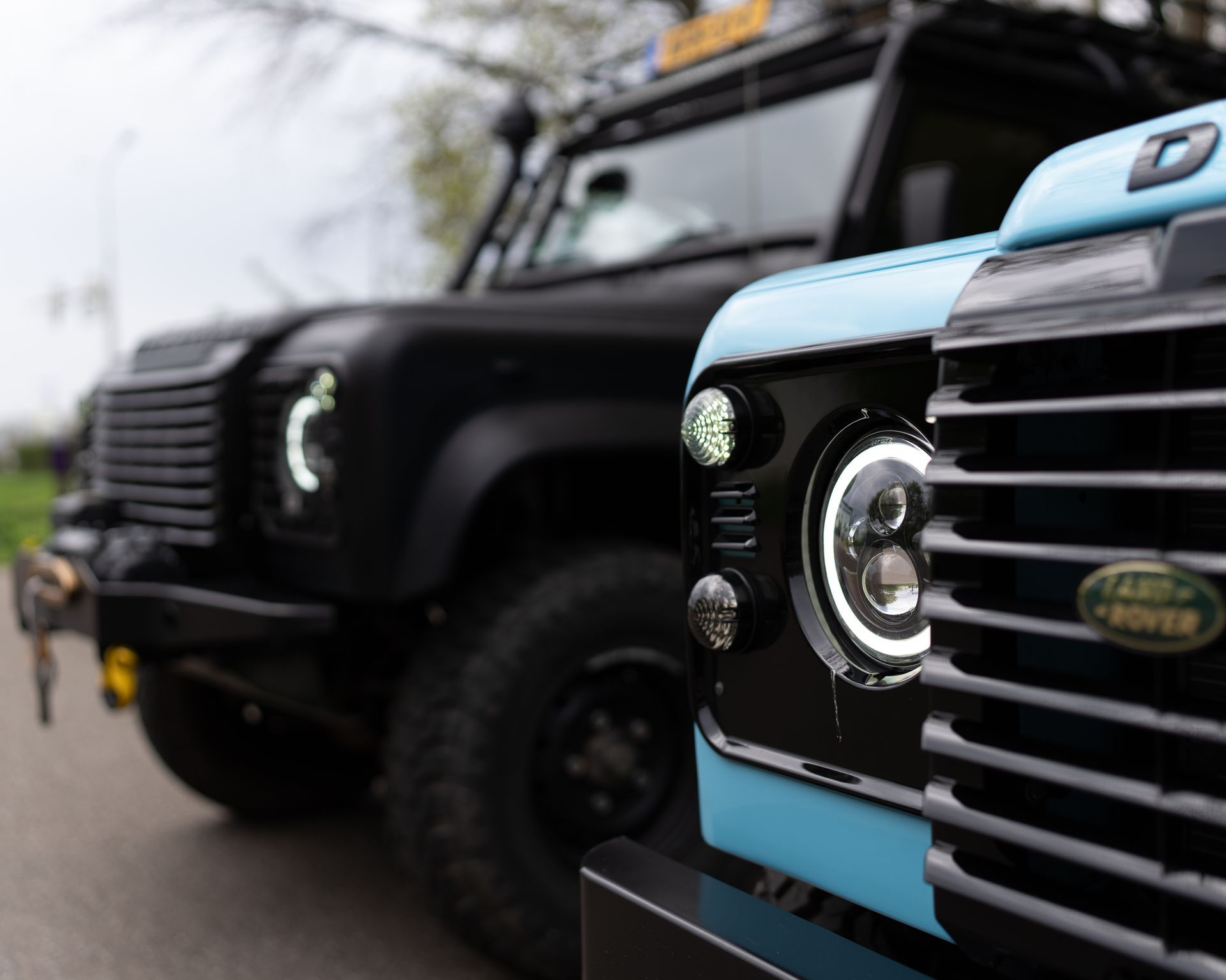 Twee Land Rover Defenders staan naast elkaar op een weg geparkeerd.
