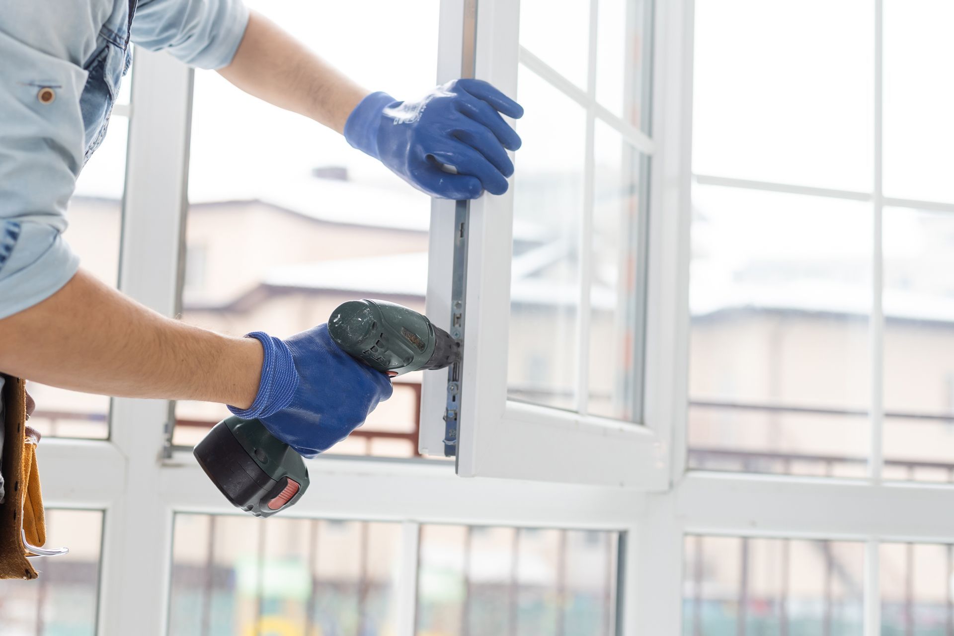A Man is Installing a Window With a Drill