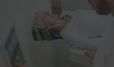 A woman is laying in a hospital bed getting an x-ray of her head.
