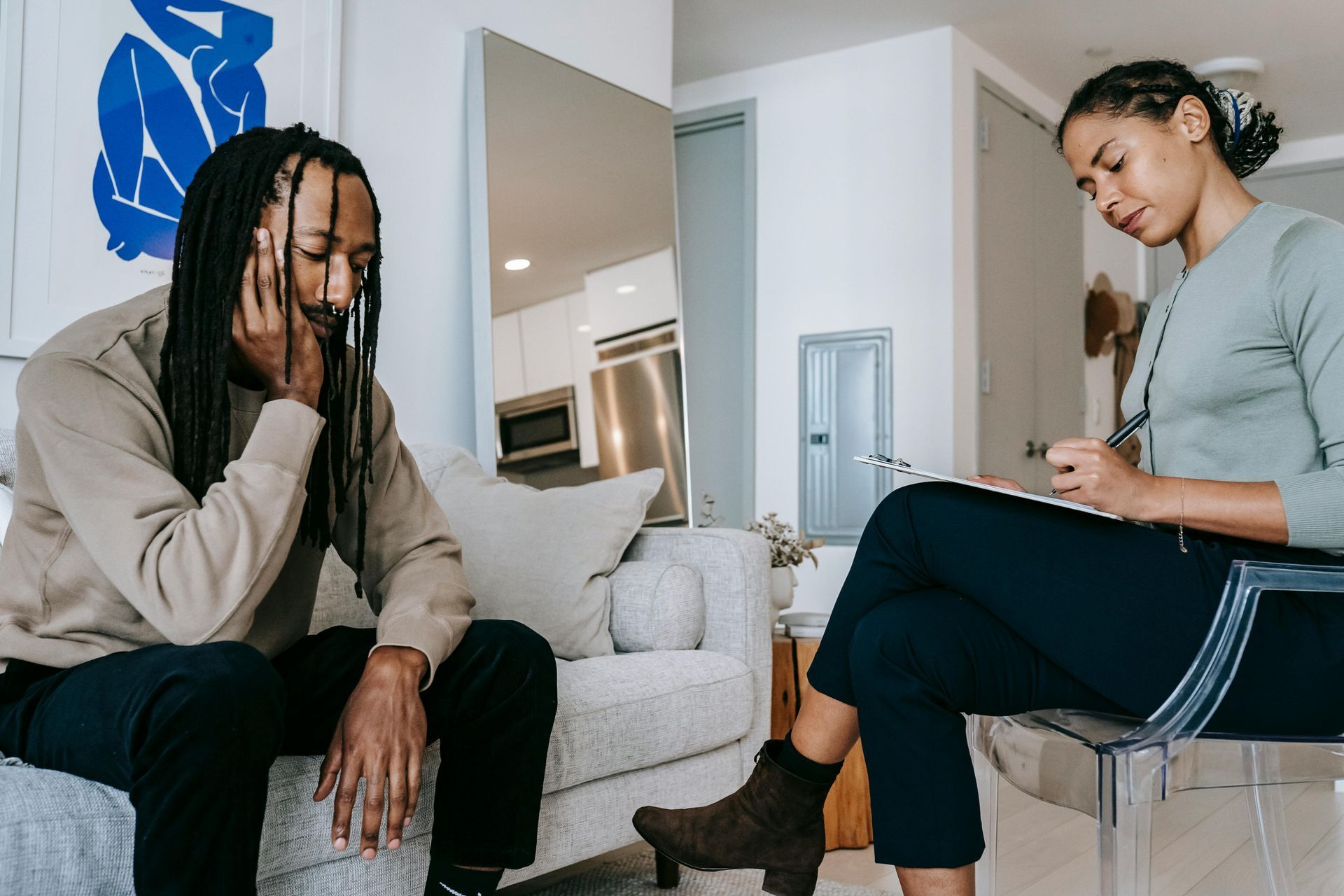 A man is sitting on a couch talking to a woman who is sitting in a chair.