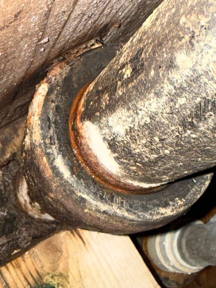 Close-up of a rusty metal joint and bearing with orange corrosion on worn machinery.