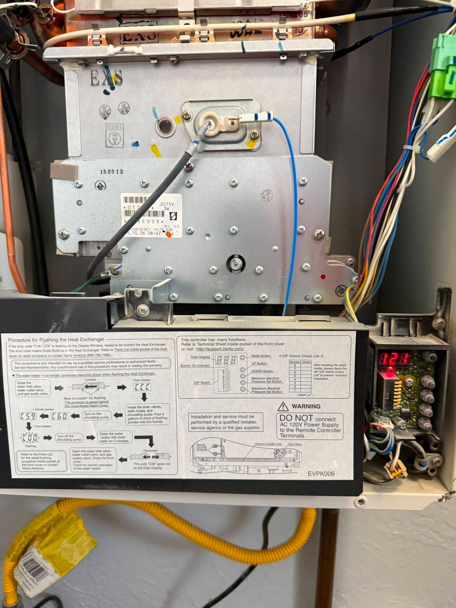 Open appliance with wiring, metal panel, and handwritten service notes on the inside door.