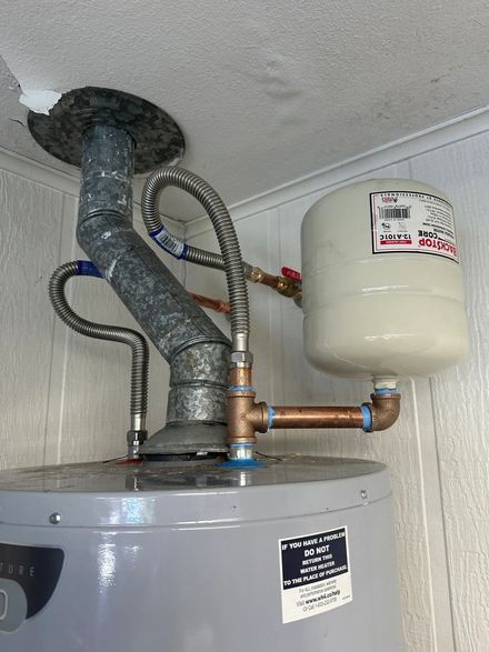 Water heater with venting pipes and expansion tank in a utility closet