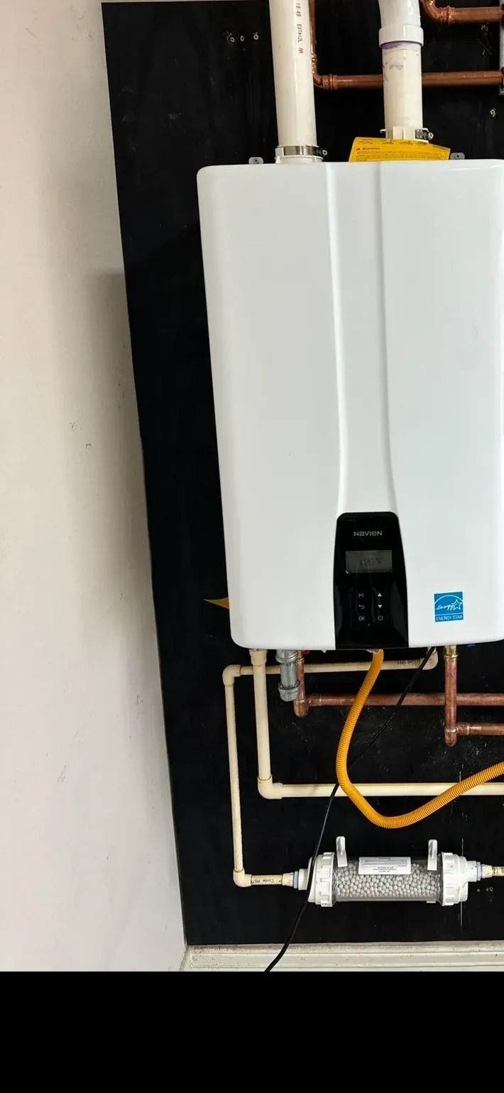 White wall-mounted boiler with copper and yellow pipes in a utility area