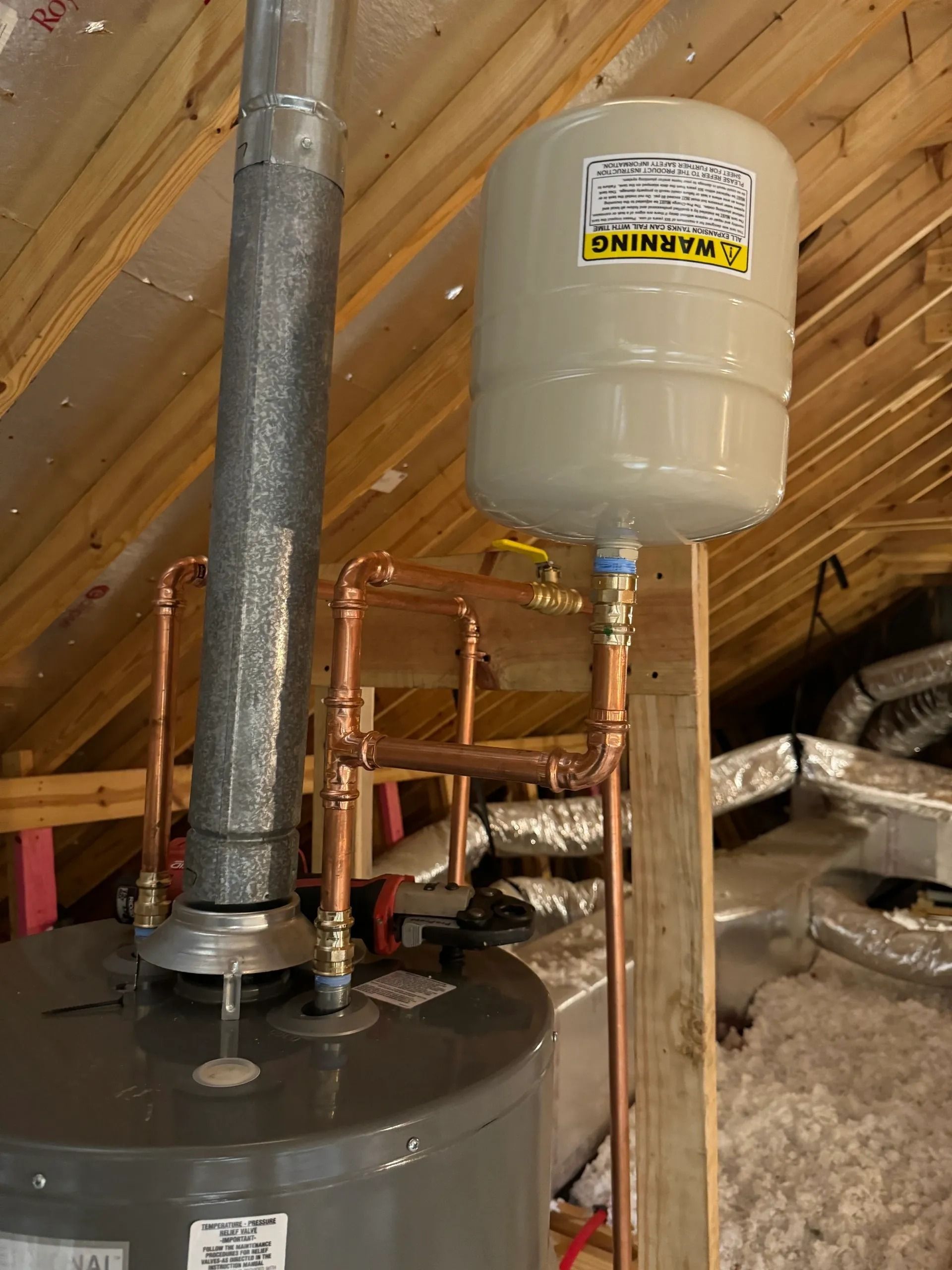Water heater and expansion tank in an attic with exposed insulation and ductwork