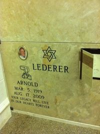 Memorial plaque on a beige stone wall with a Star of David, name, dates, and candle holder