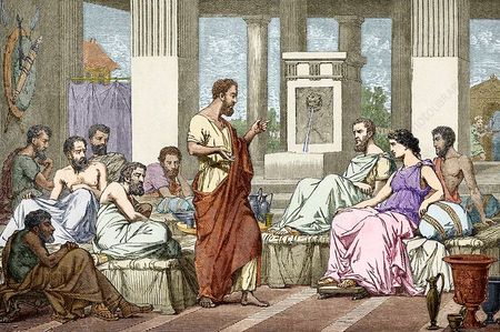 A bearded man in a toga speaks to a group of people seated in a classical setting.
