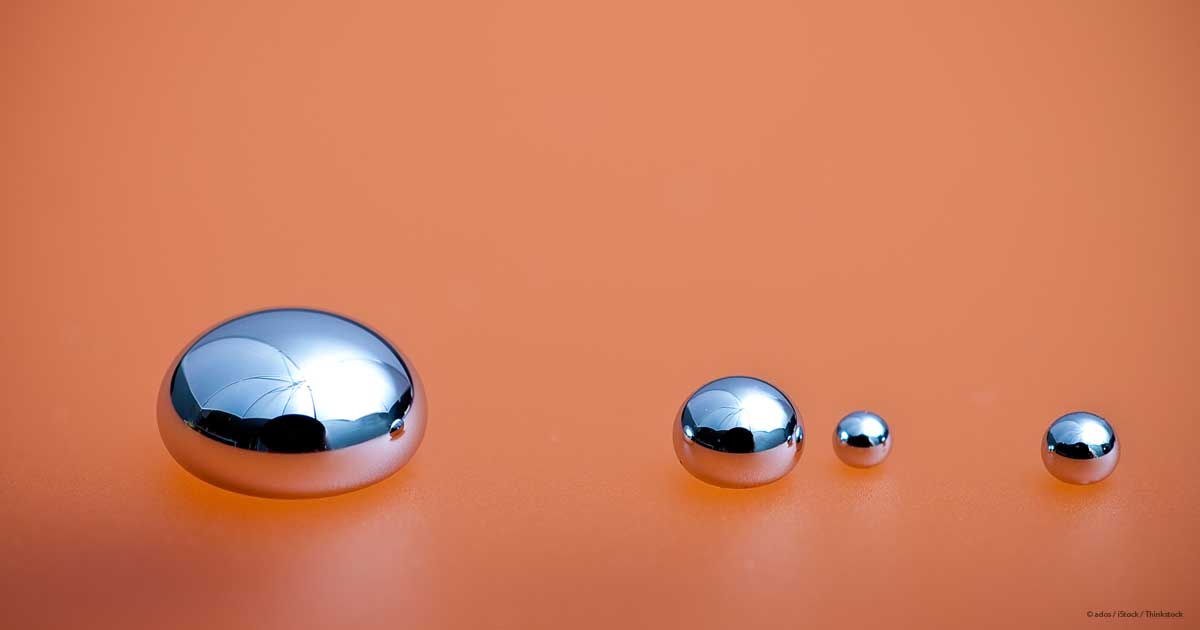 Four silvery liquid mercury spheres on an orange surface, increasing in size.