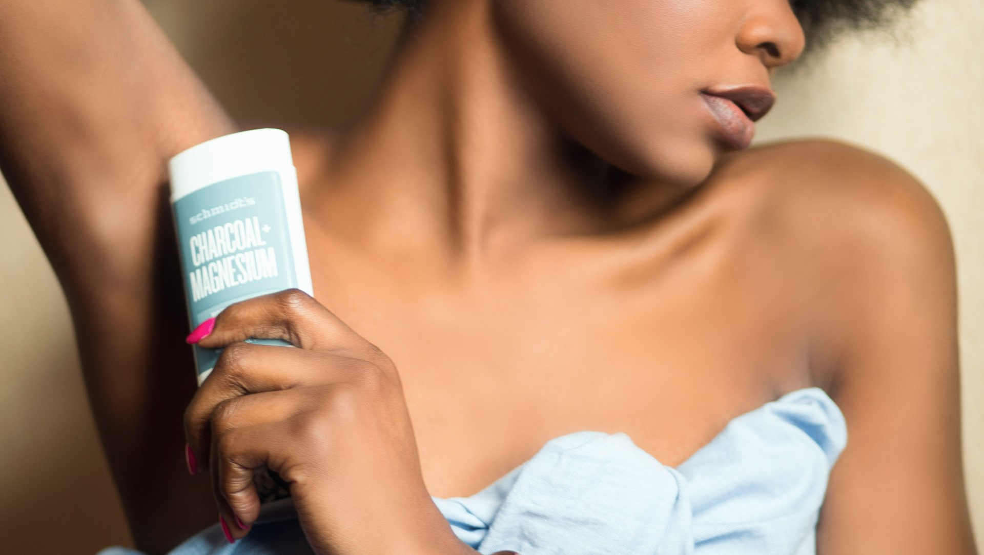 Woman applying charcoal magnesium deodorant.