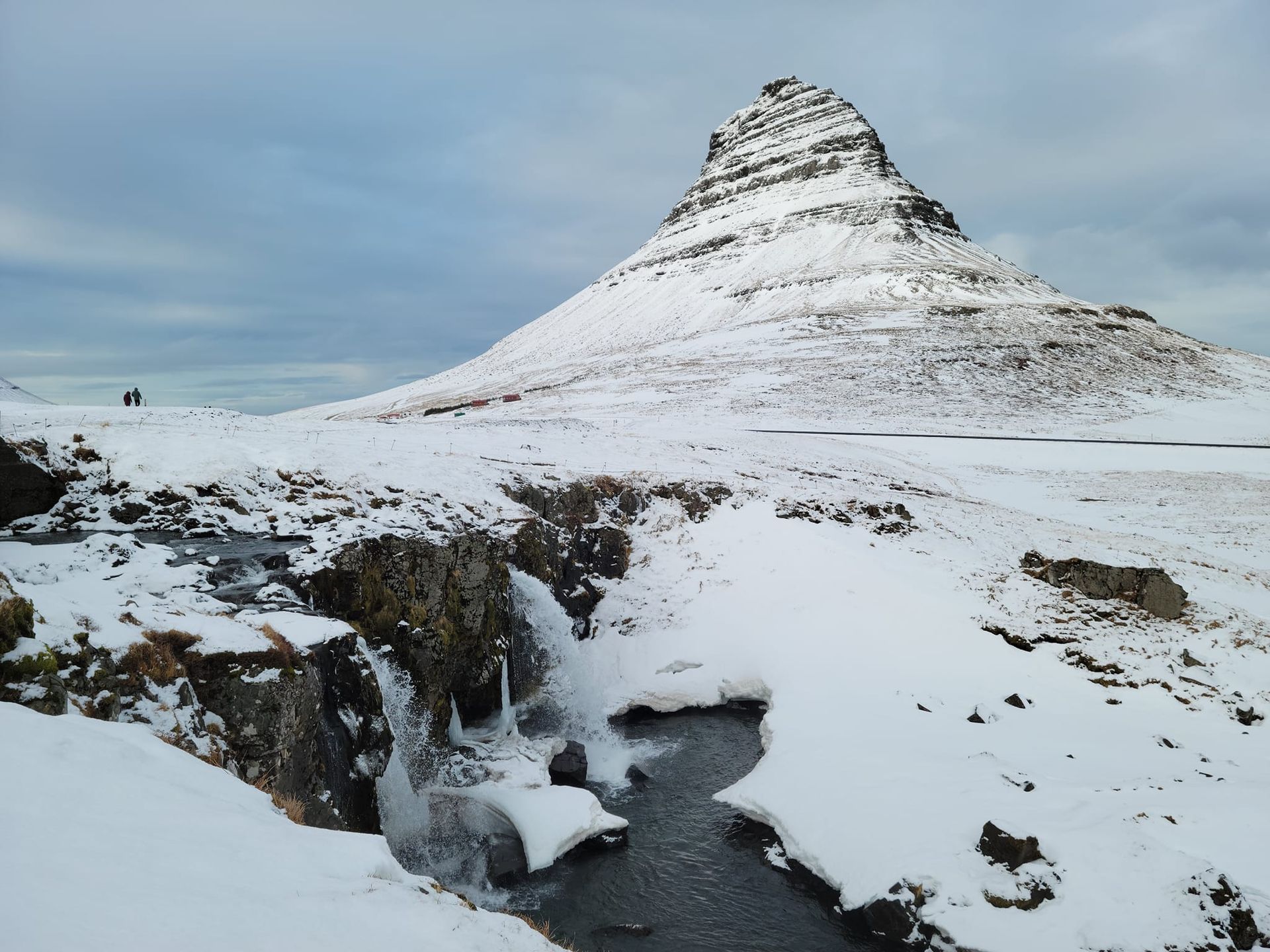 Snow-covered mountain rising up in the background, with a small waterfall in the snow-covered foreground.