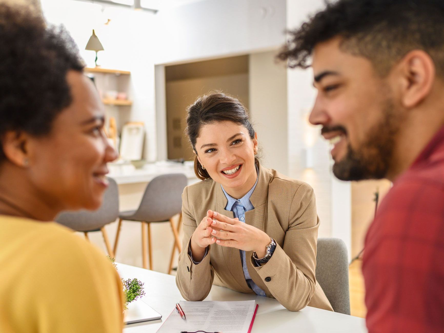 a woman is sitting at a table talking to a man and woman .