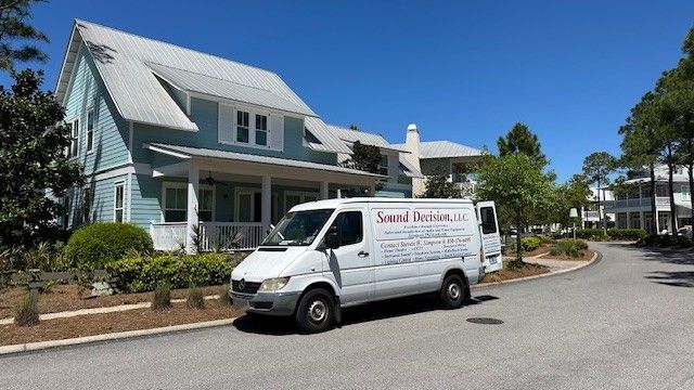 White service van parked by a light-blue house on a sunny street under a clear blue sky