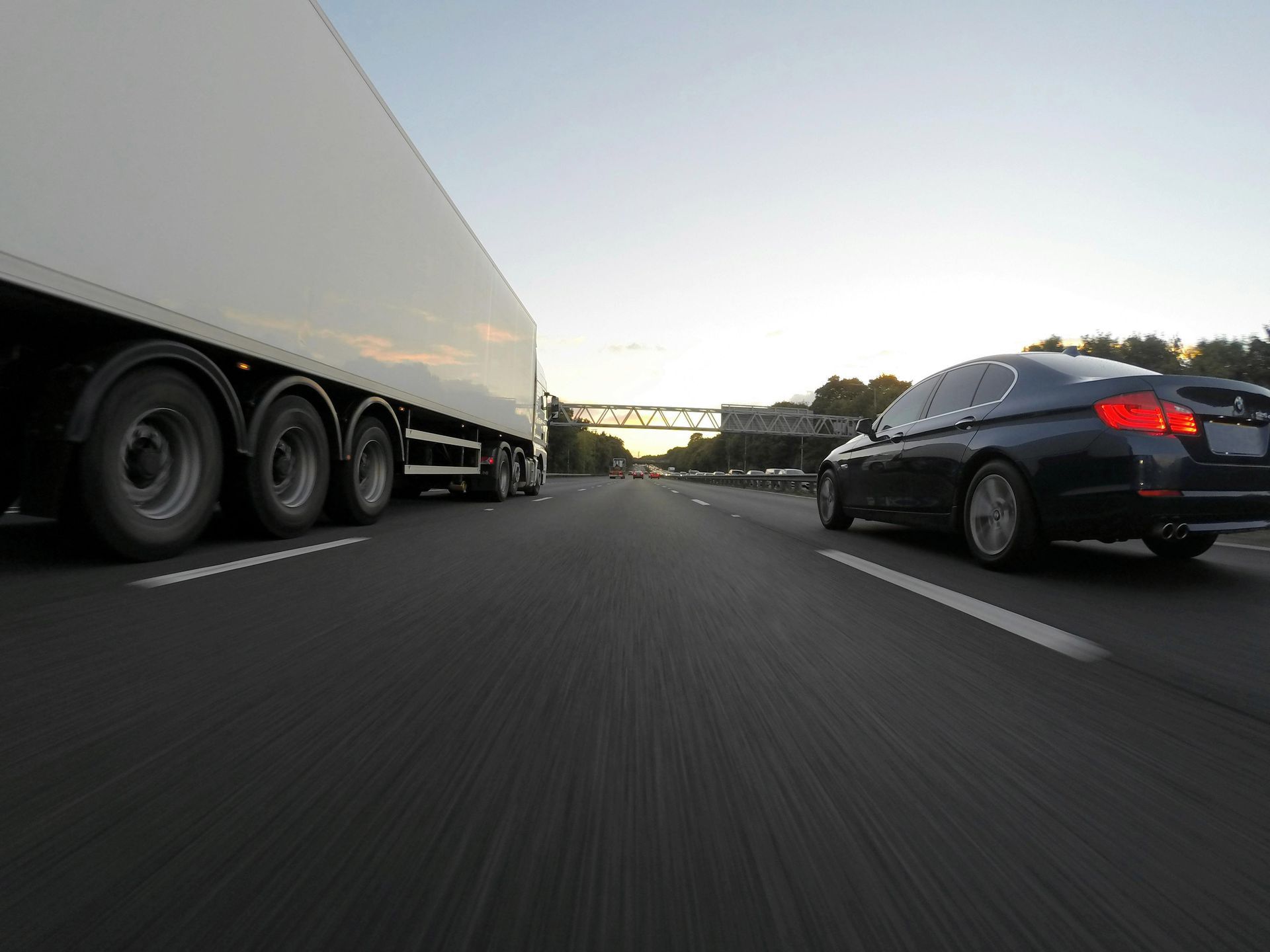 A tractor trailer and car speeding down the highway