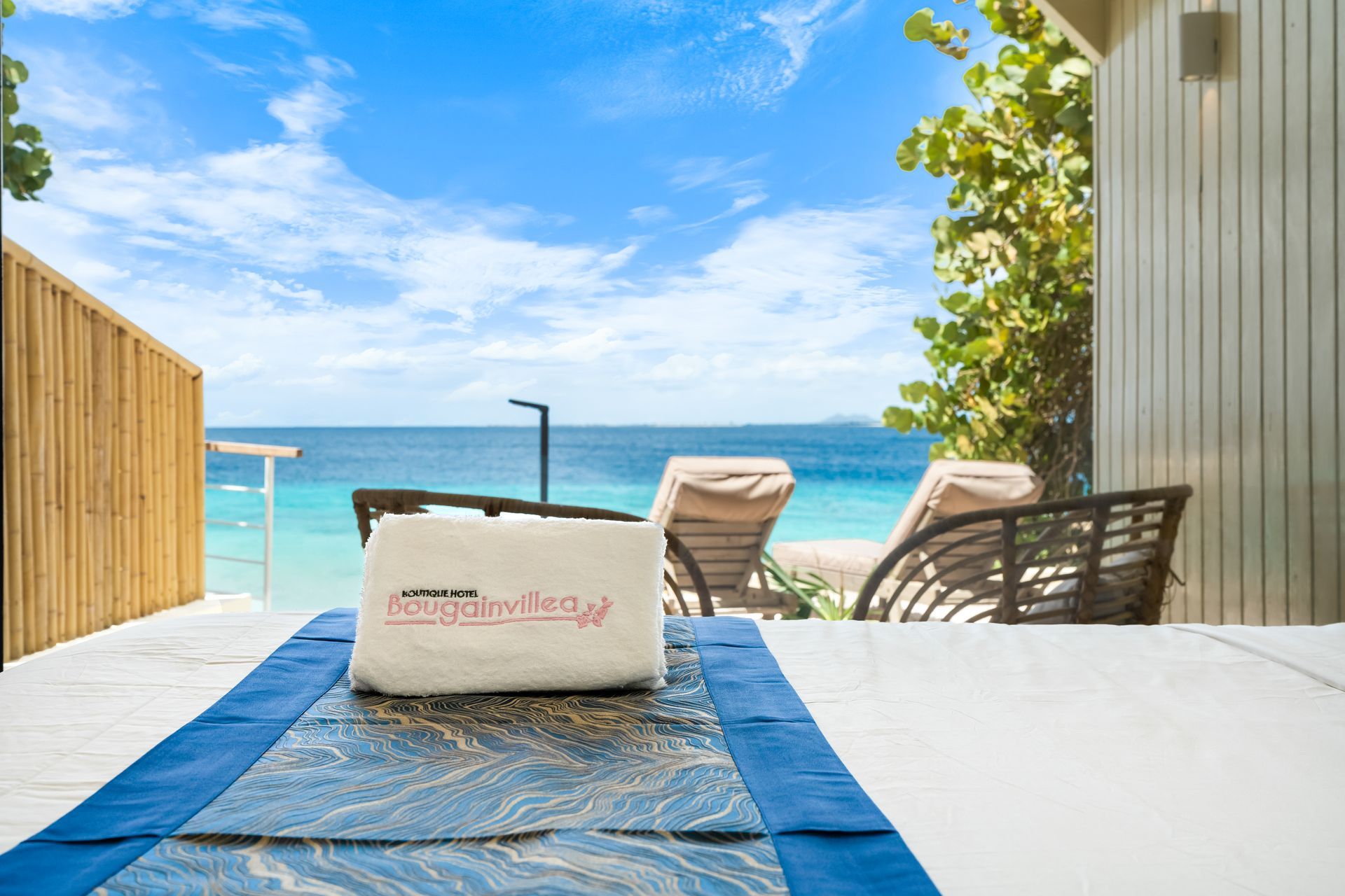 Beachside patio with lounge chairs, table, and ocean view under a blue sky