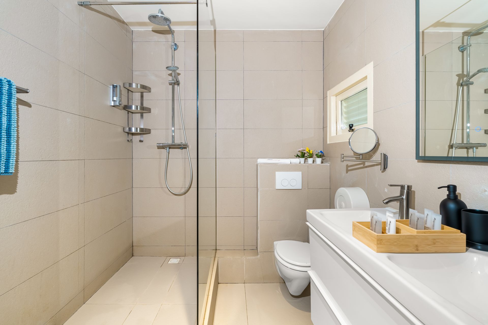 Modern beige bathroom with walk-in shower, toilet, and sink vanity