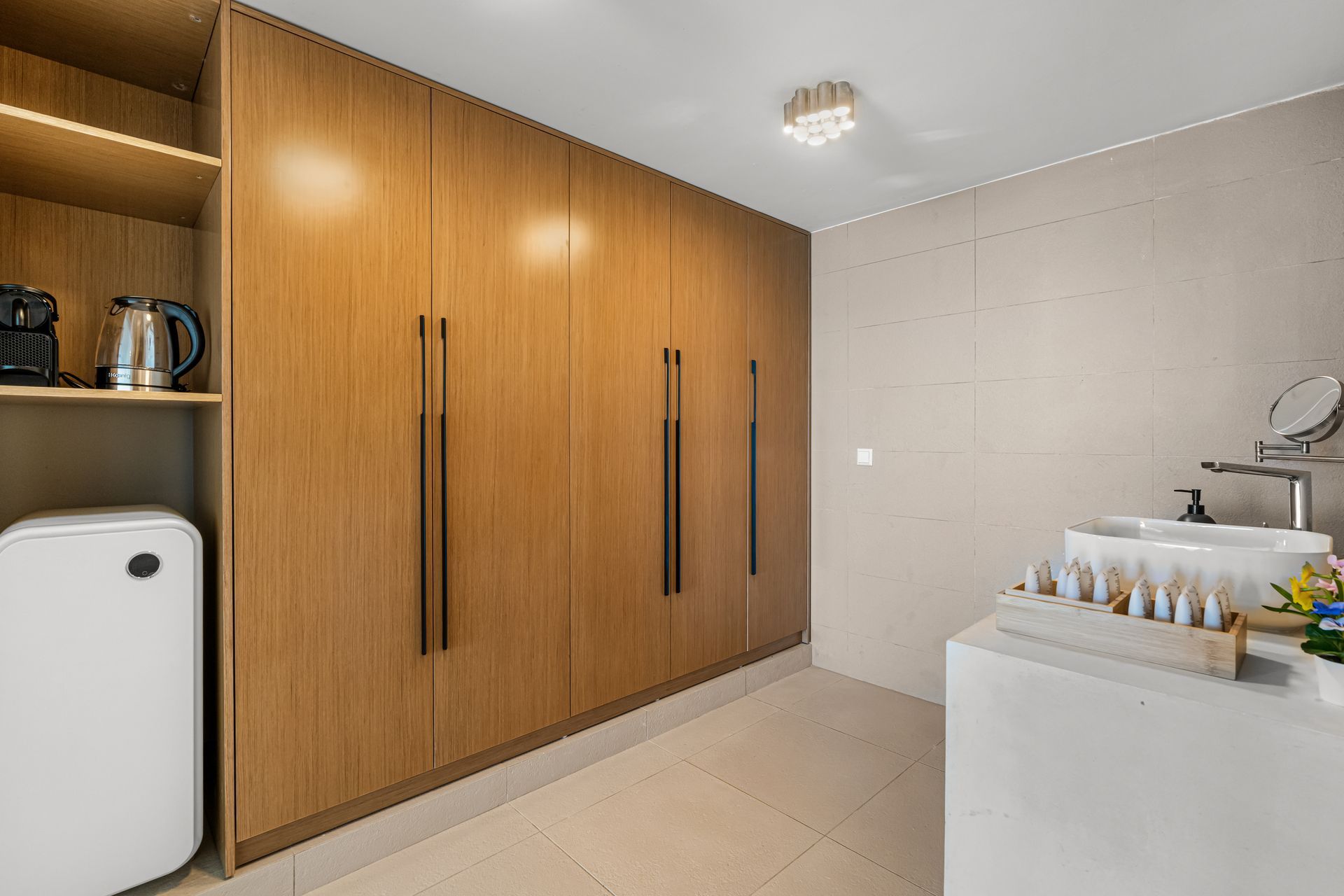 Modern kitchen with wood cabinets, white island, beige walls, and a dining nook in the background