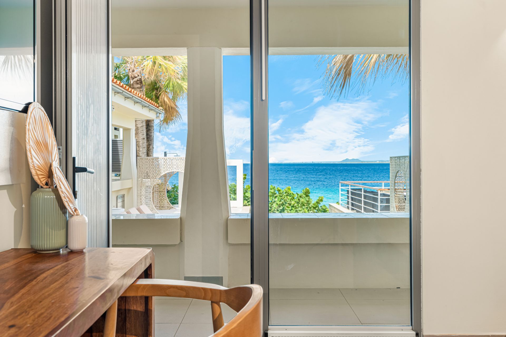 Wooden desk with ocean view seen through sliding glass doors.