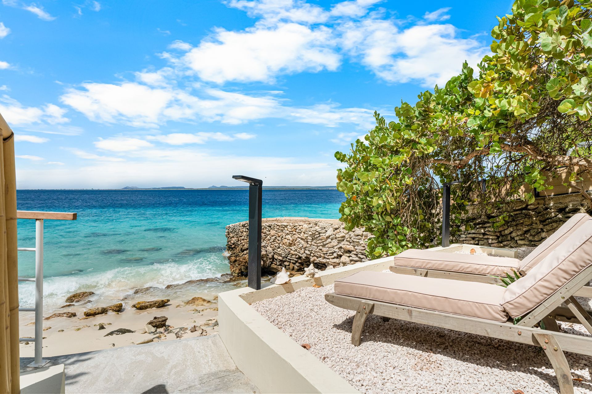 Beachfront lounge chairs beside turquoise water under a blue sky