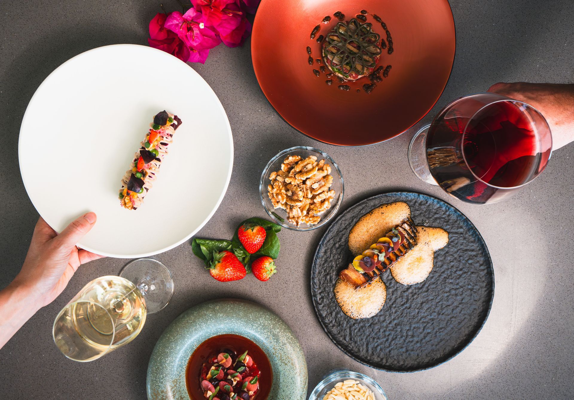 Top-down view of a plated meal with wine, fruit, and desserts on a table