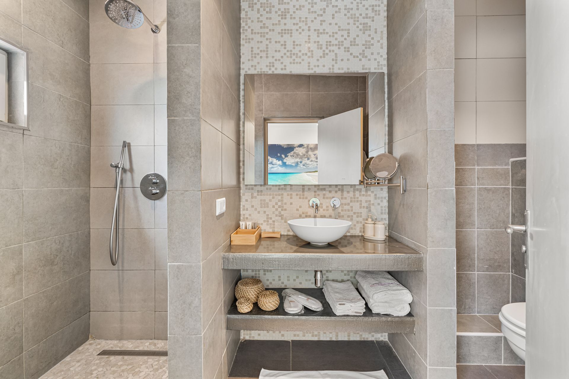 Modern bathroom vanity with round sink, mirror, open shelves, and tiled shower area