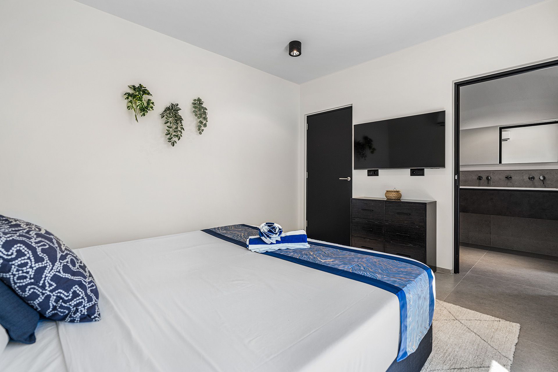 Bedroom with bed, TV, black door, and open doorway to a kitchen area.
