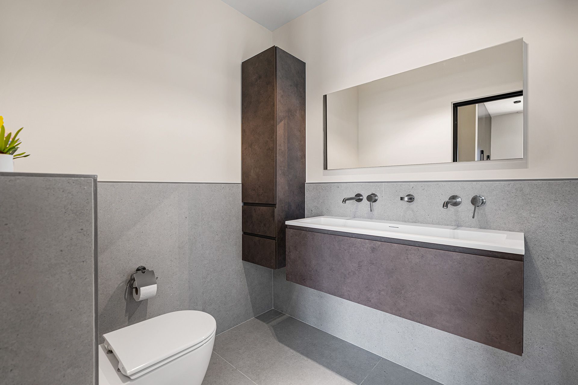 Modern bathroom with grey walls, floating vanity, large mirror, and a toilet.
