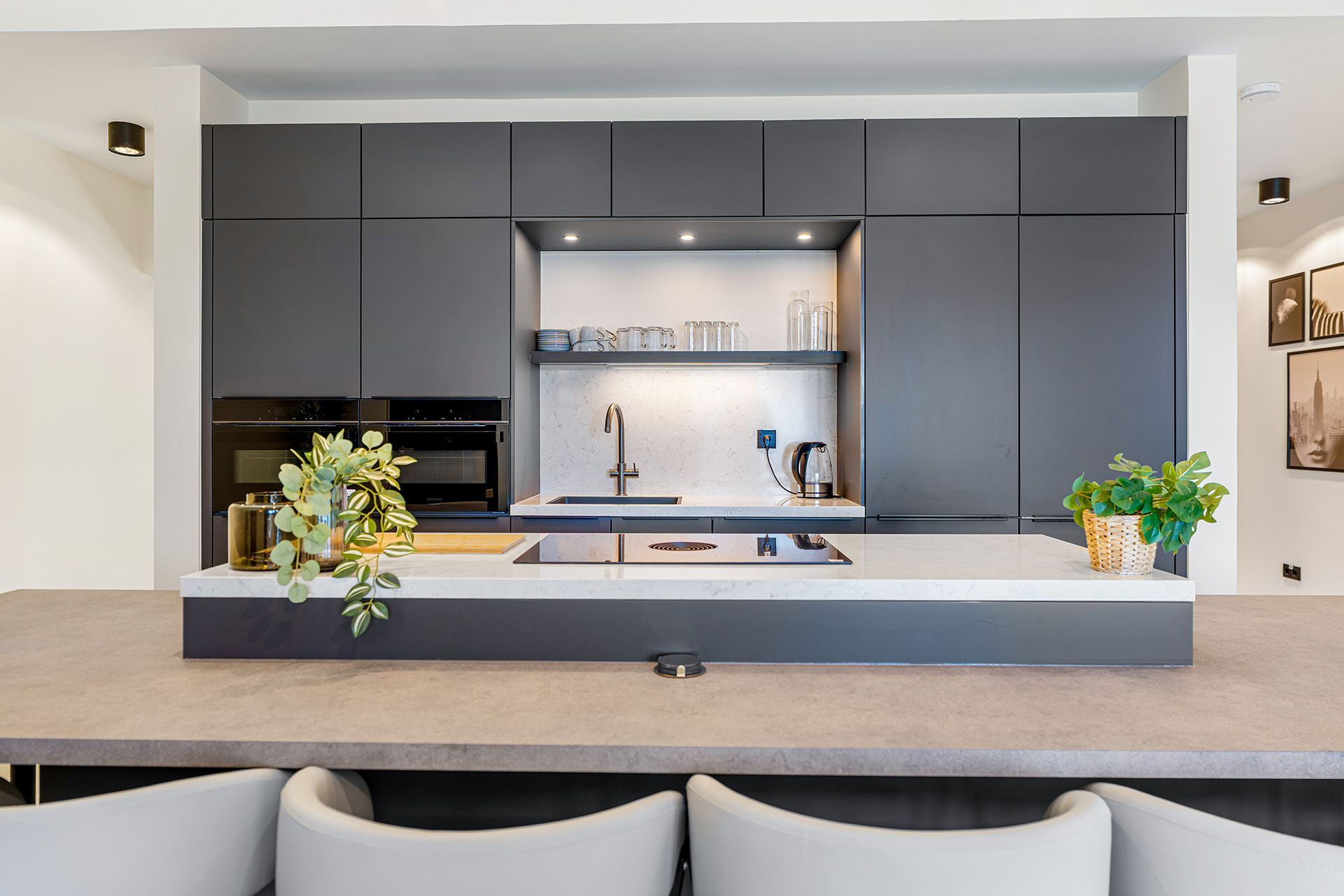 Modern kitchen with dark gray cabinets, a sink, and a countertop with seating.