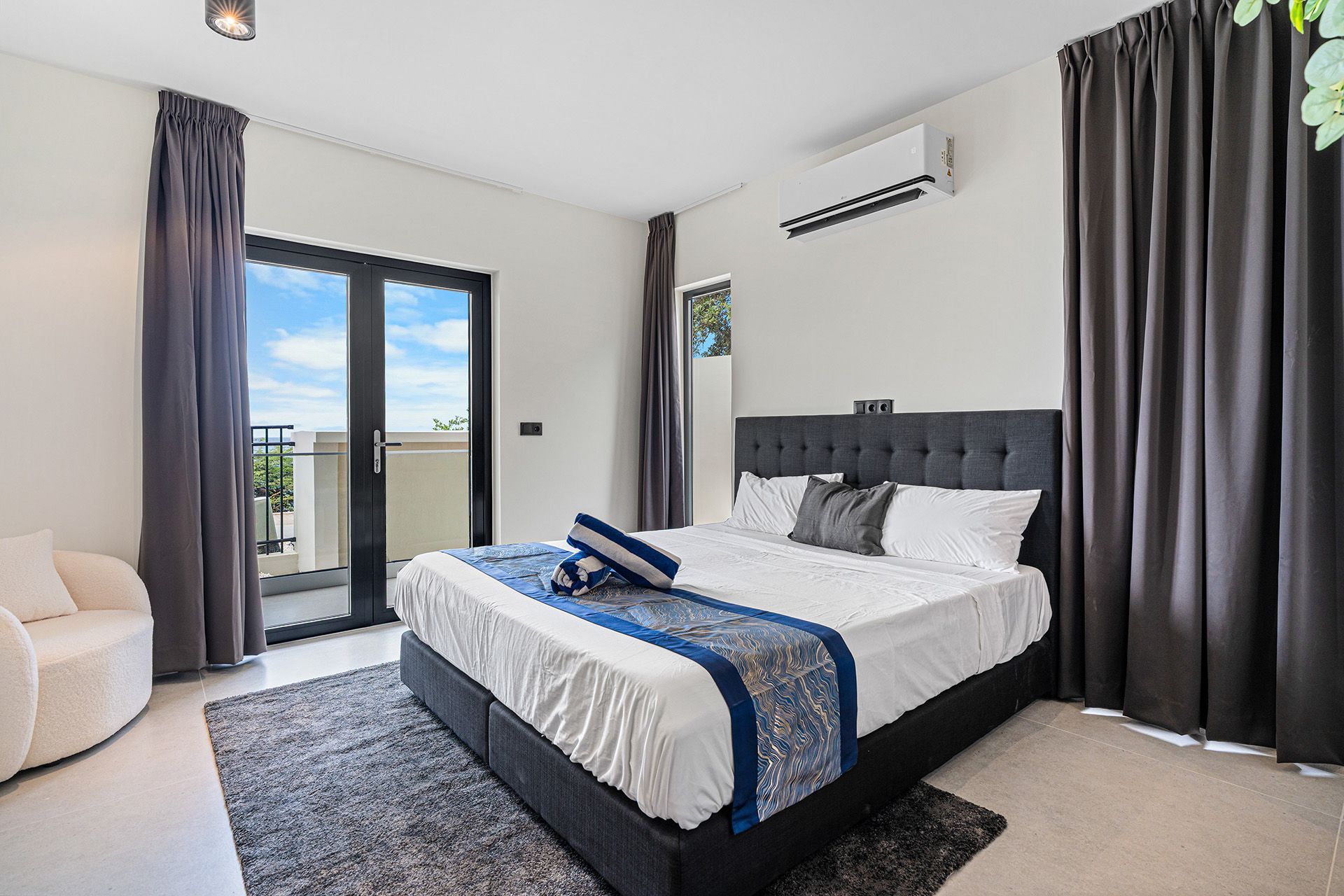 Bedroom with a bed, balcony doors, gray curtains, and an AC unit.