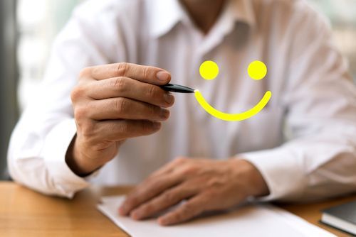 A person wearing a white shirt drawing a yellow smiley face on the screen.