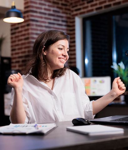 A happy client in a white shirt, sitting at a desk.