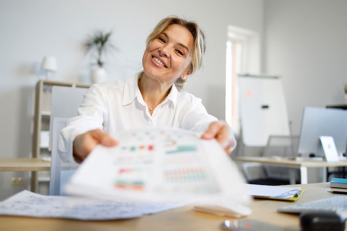 Woman handing papers with a smile, representing Smart Tax Solutions' services.