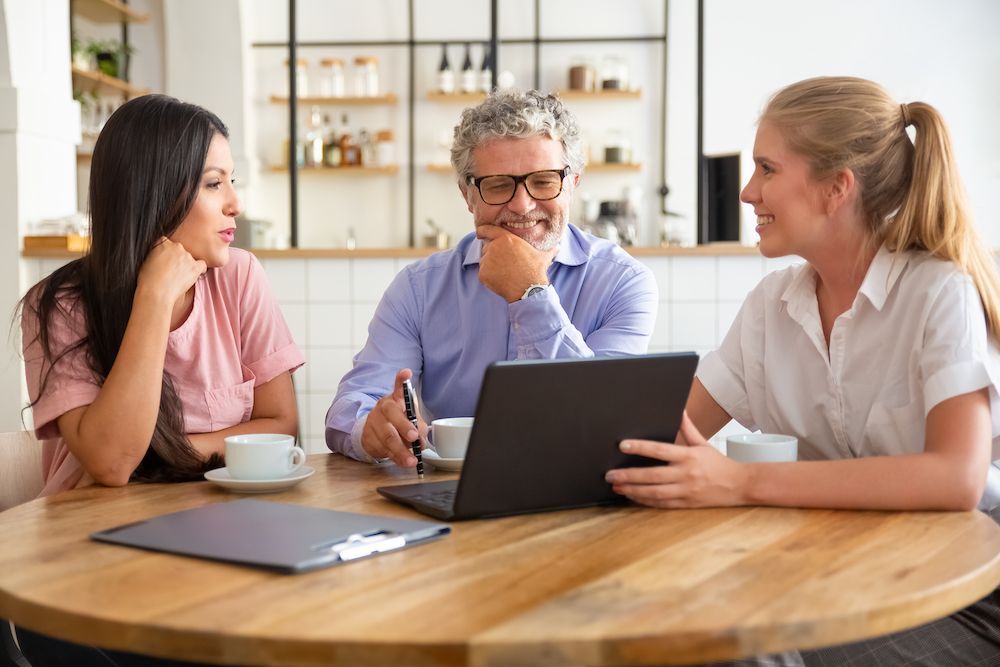 Three people discussing strategies with clients over laptop in the office