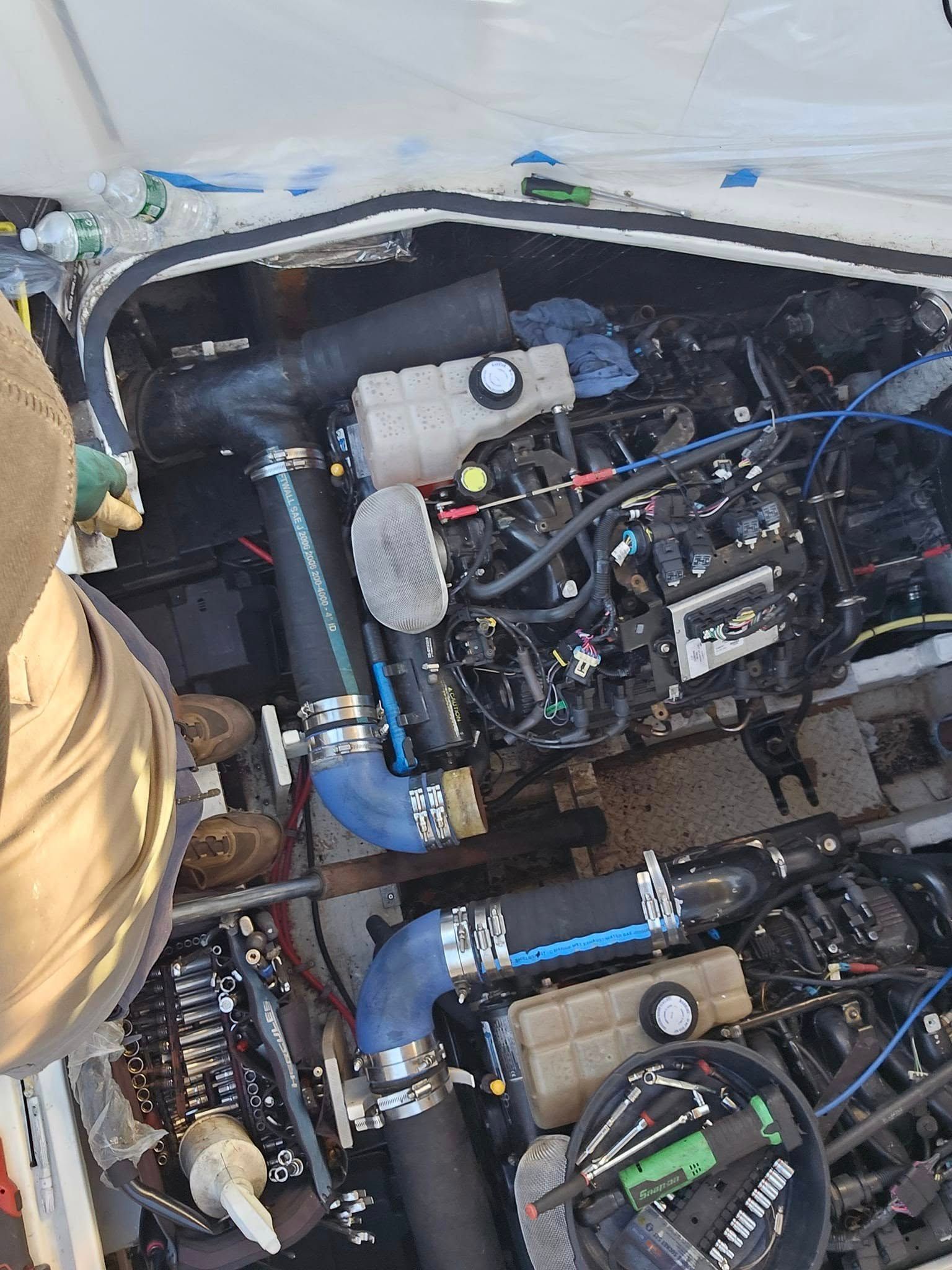Close-up of a boat engine compartment with two engines, hoses, and wiring visible