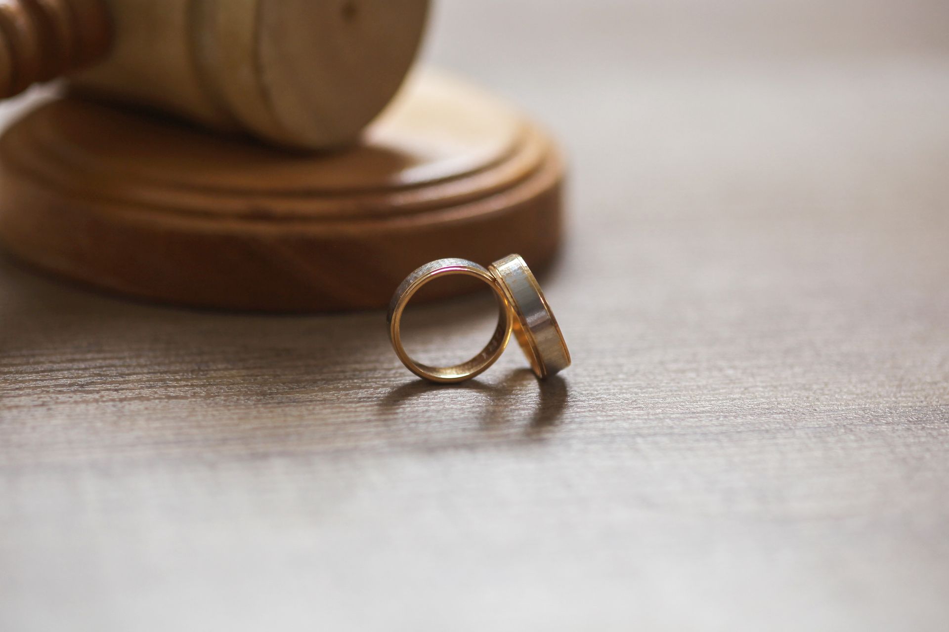 Wedding rings beside a judge’s gavel on a wooden desk