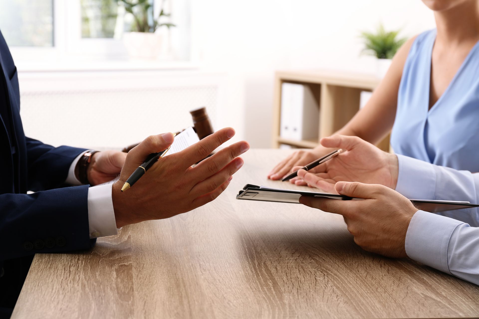 Two people discussing documents across a wooden table in a bright office setting