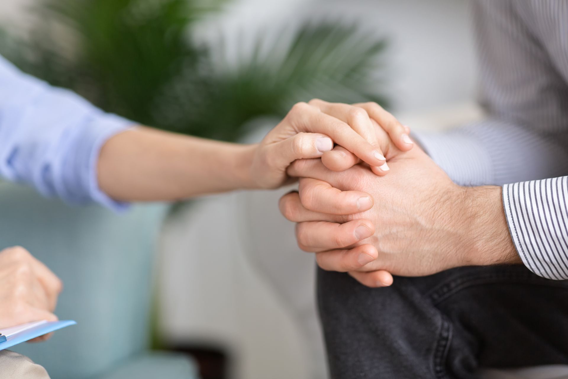 Two people holding hands in a supportive conversation setting
