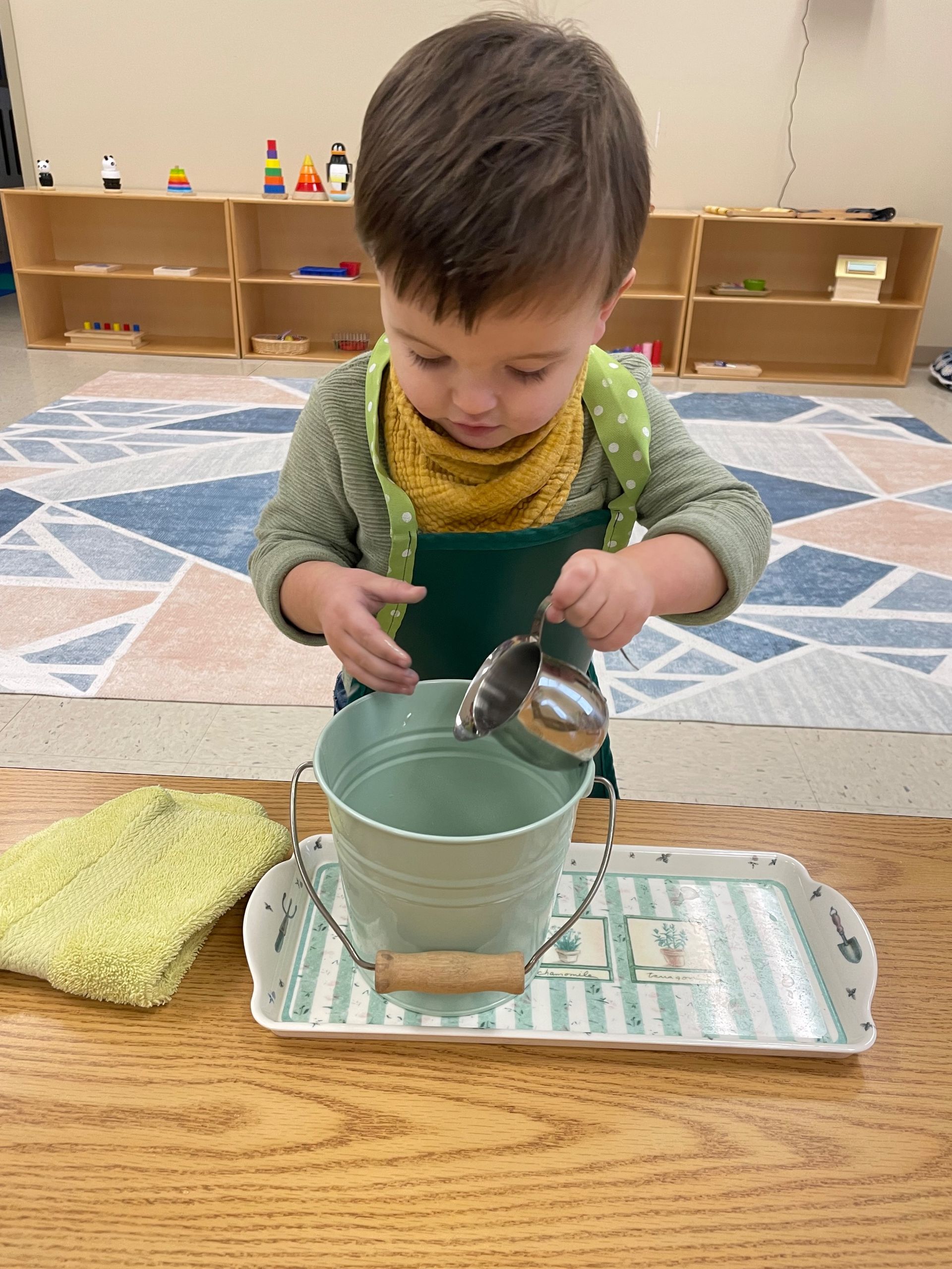 a Montessori child is pouring water into a bucket