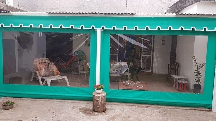 Barra exterior con listones de madera, pared de ladrillo, encimera negra y plantas en macetas.