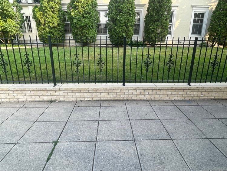 A wrought iron fence with a brick wall behind it