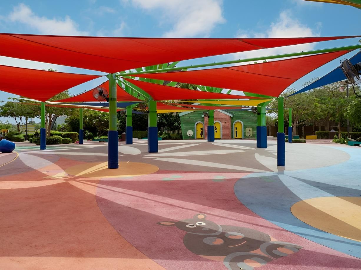 A Park with A Lot of Colorful Umbrellas and A Building in The Background — Jon Wilson Canvas & Shade in Coffs Harbour, NSW