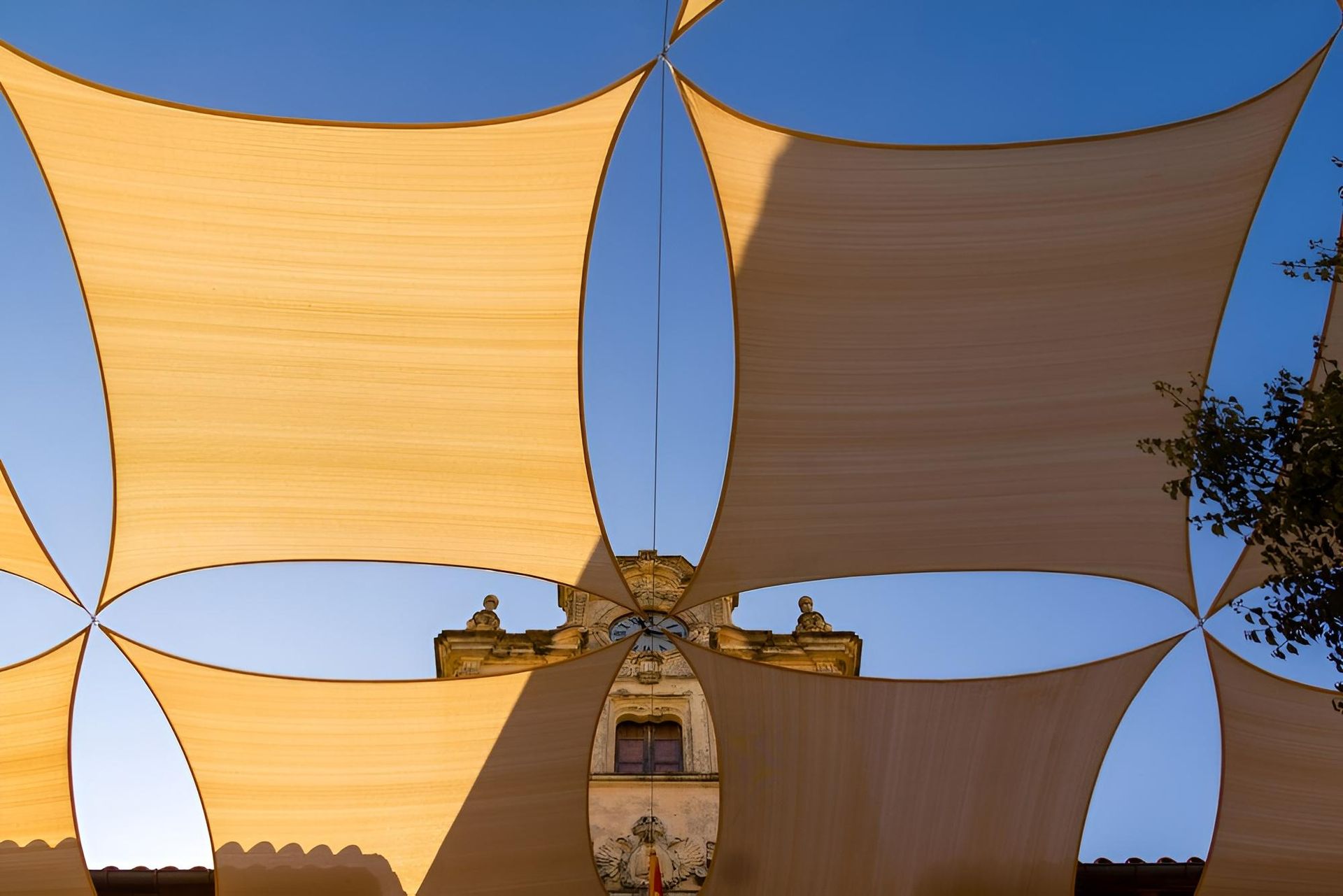 A Large Umbrella Is Hanging from The Side of A Building — Jon Wilson Canvas & Shade in Coffs Harbour, NSW