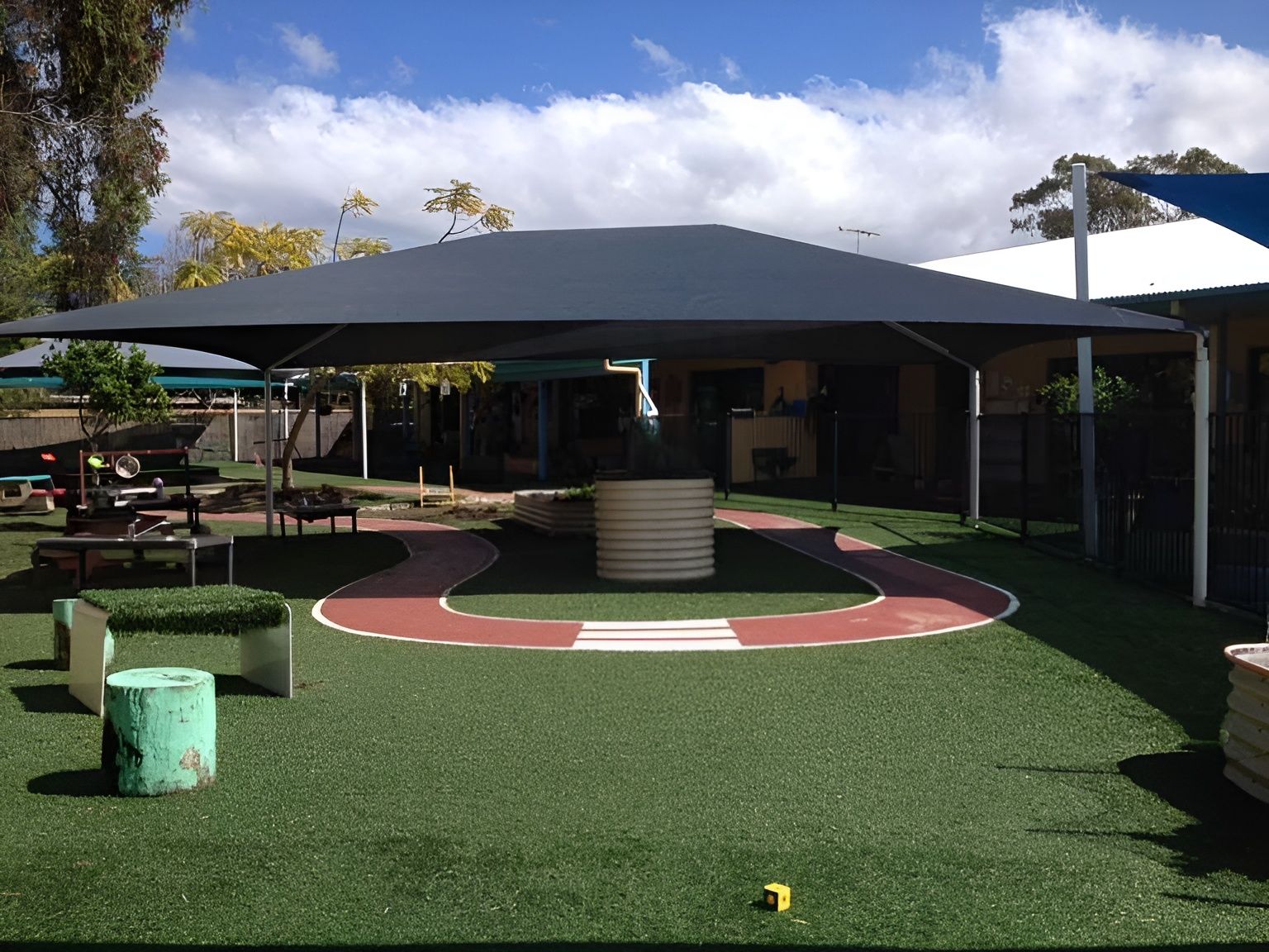 A Large Umbrella Is Sitting on Top of A Lush Green Field — Jon Wilson Canvas & Shade in Port Macquarie, NSW